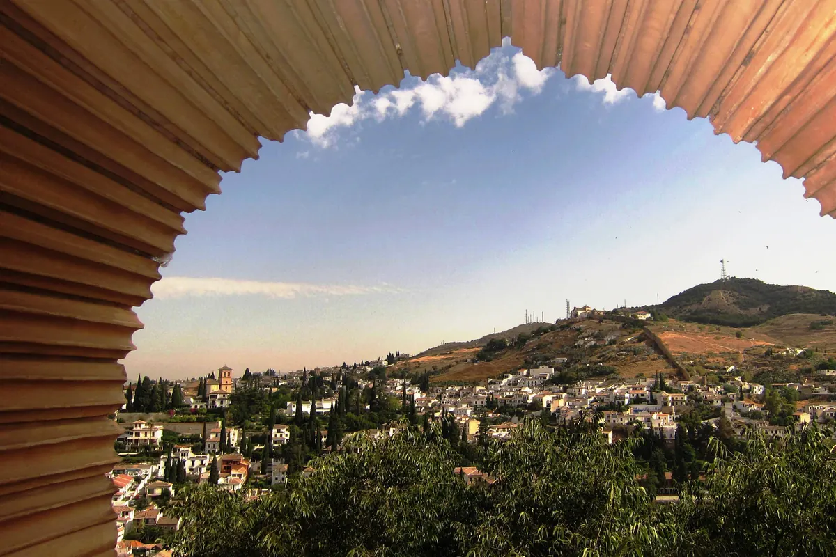 The Sacromonte hill seen through a scalloped arch in the Nasrid Palaces of the Alhambra