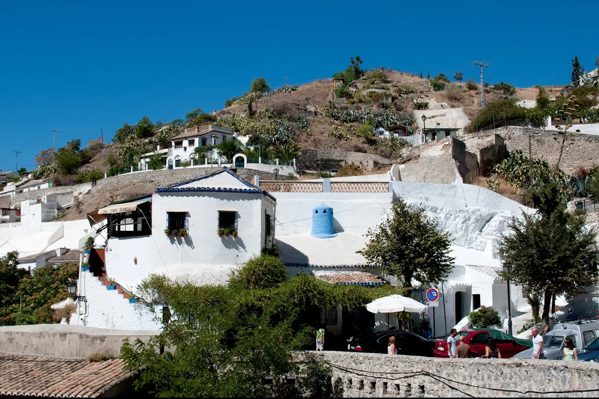 Whitewashed houses and cave dwellings stepping up the Sacromonte hillside beneath clear sky